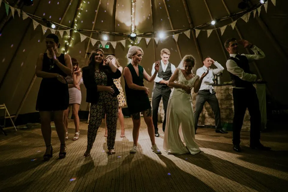 Novia e invitados bailando de noche bajo guirnaldas de luces y banderines