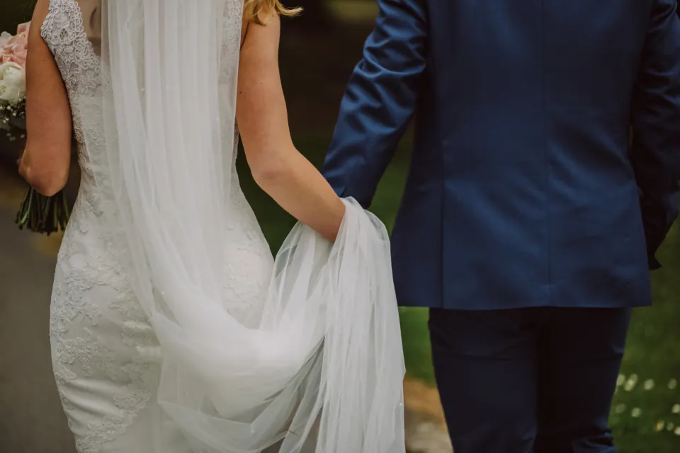 Novios caminando de la mano, detalle del vestido en una boda en Granada