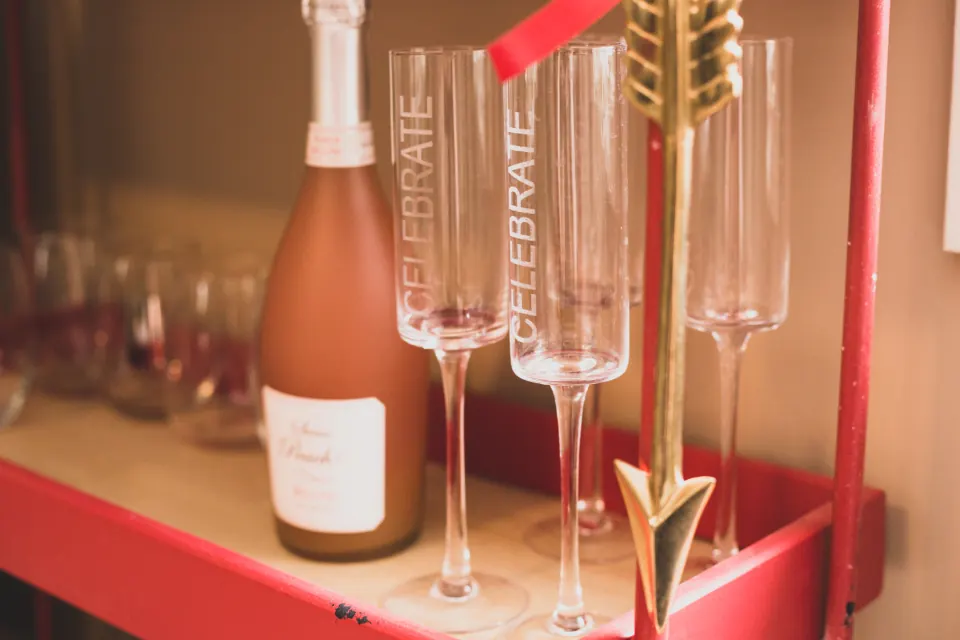 Botella de cava rosado y copas sobre una barra roja en una fiesta privada en Granada